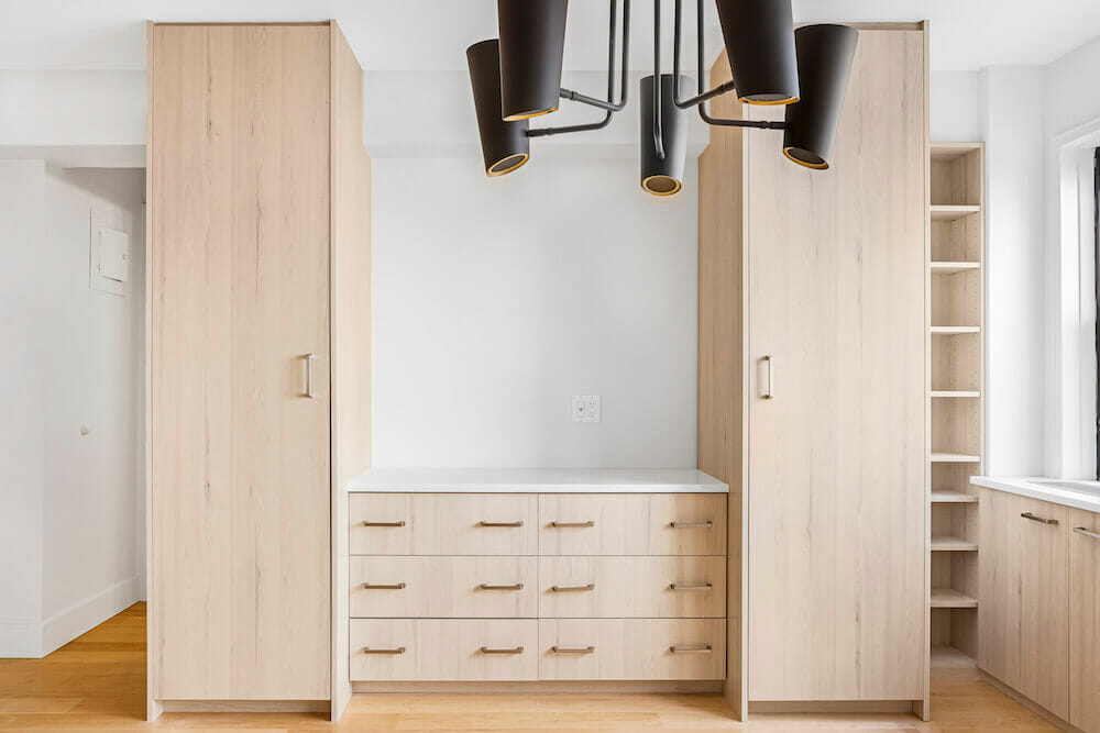 Matte black light fixtures in a studio apartment with wooden flooring and cabinetry after renovation