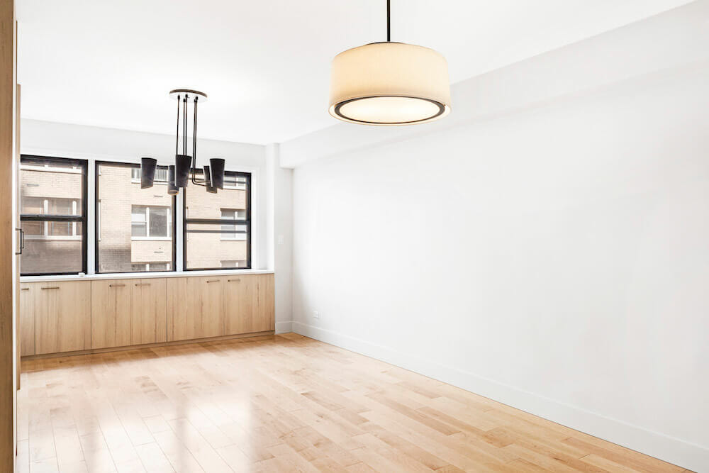 Studio apartment with maple wooden flooring and closed cabinetry over glass windows after renovation
