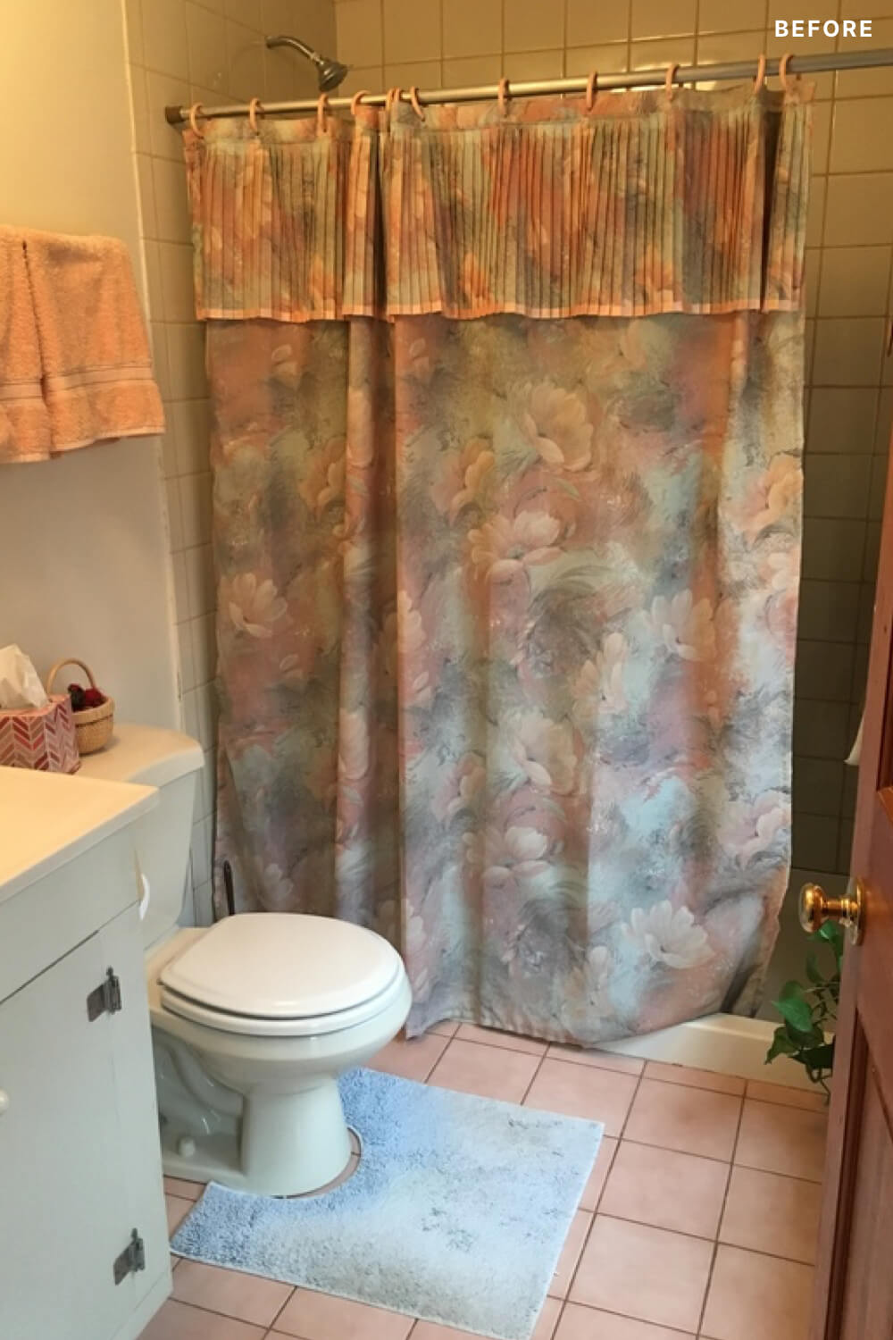 Floral orange shower curtain with orange floor tile and white toilet before renovation