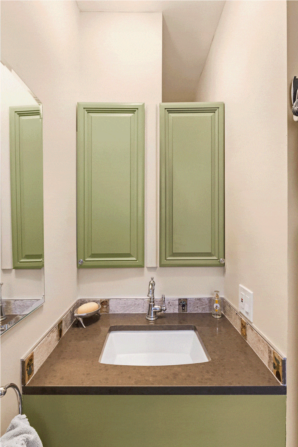 Green slide out shelves over an in built white sink and granite countertop after renovation