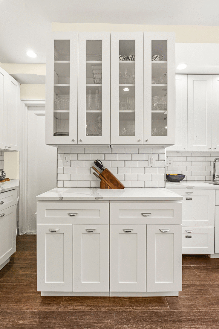 white glass panelled kitchen cabinets over marble countertop and closed kitchen cabinets underneath after renovation