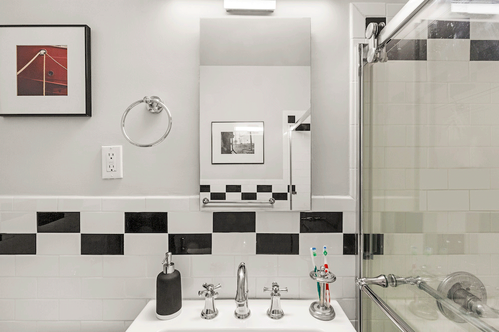 white and gray bathroom with long vanity mirror and brushed nickel faucet after renovation