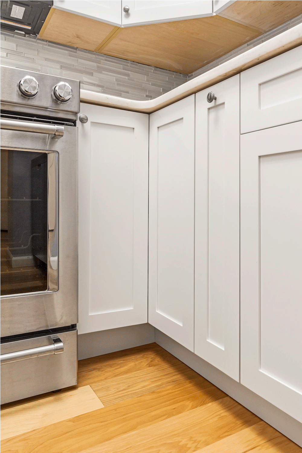 white kitchen cabinets with gray knob and silver appliance along with gray backsplash after renovation