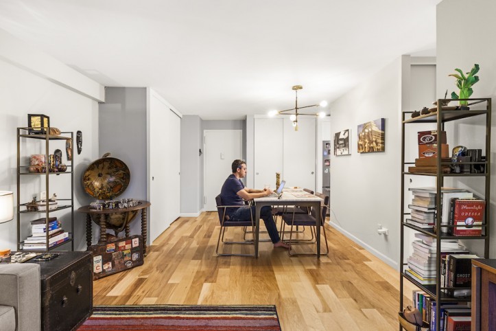 gray dining space in a natural wood flooring and a dining table with man working after renovation