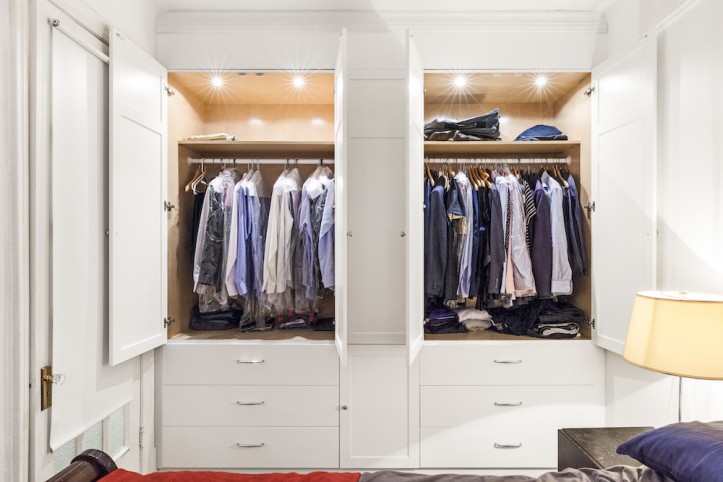 open white closet with clothes on hangers and recessed lights inside closet and white drawers after renovation