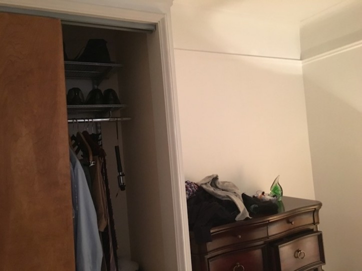 brown sliding door to a closet and dark brown chest of shelves in a bedroom before renovation
