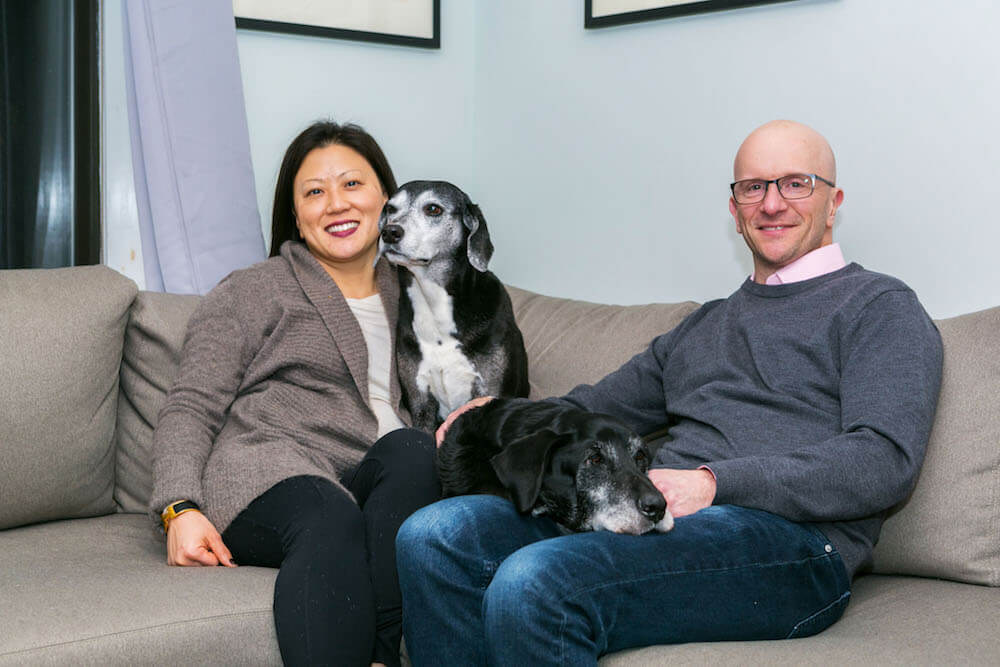 Happy homeowners sitting on the couch with their dog