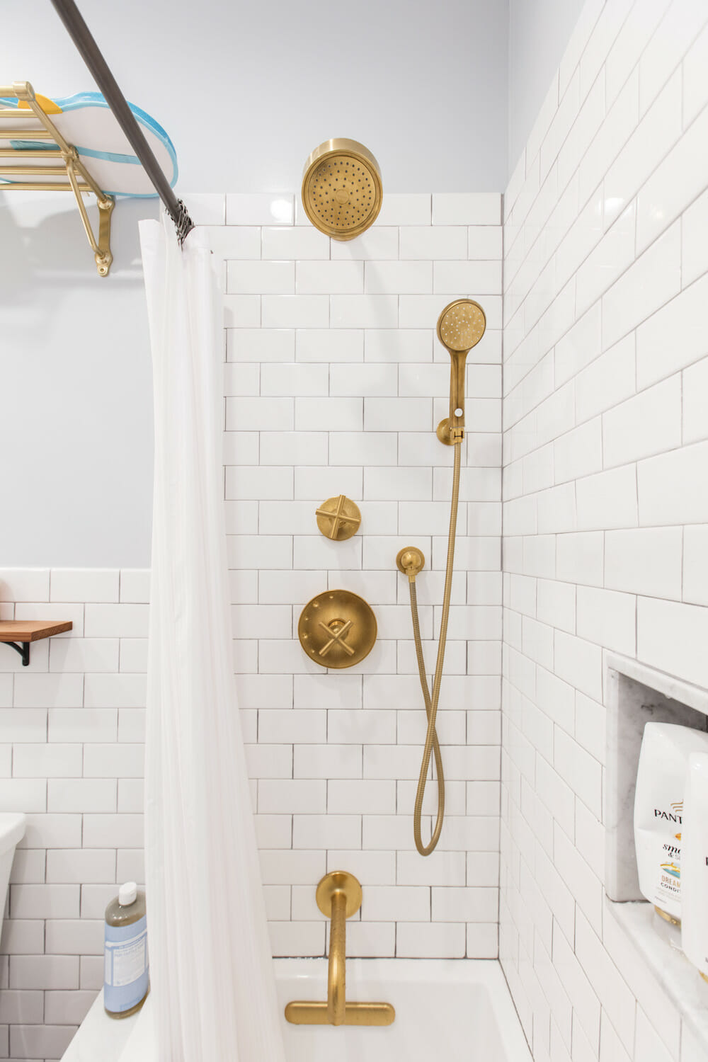 gold shower fittings with shower head in a white subway tiled bath space after renovation