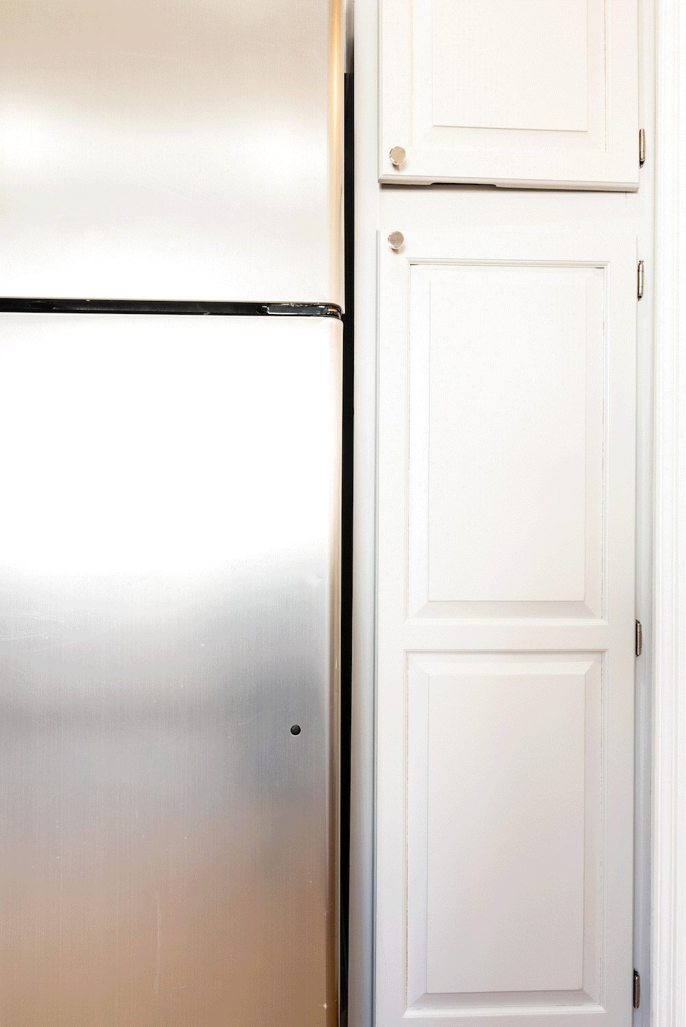 white cabinets with knobs near refrigerator before renovation