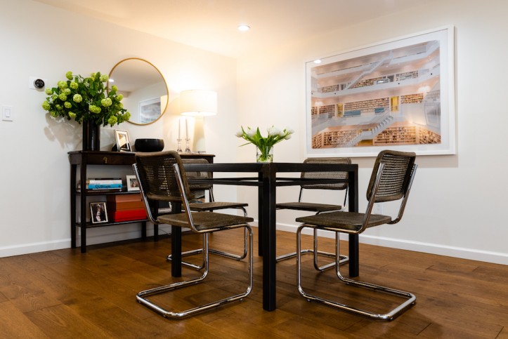 breakfast nook with chairs on a dark vinyl floor and dark brown console table below round mirror after renovation 