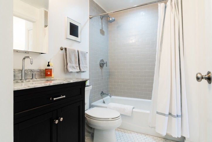 white bathroom with light brown shower wall and white bathtub with shower curtain after renovation