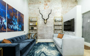 brick wall in living room with blue and white couches and a blue rug after renovation