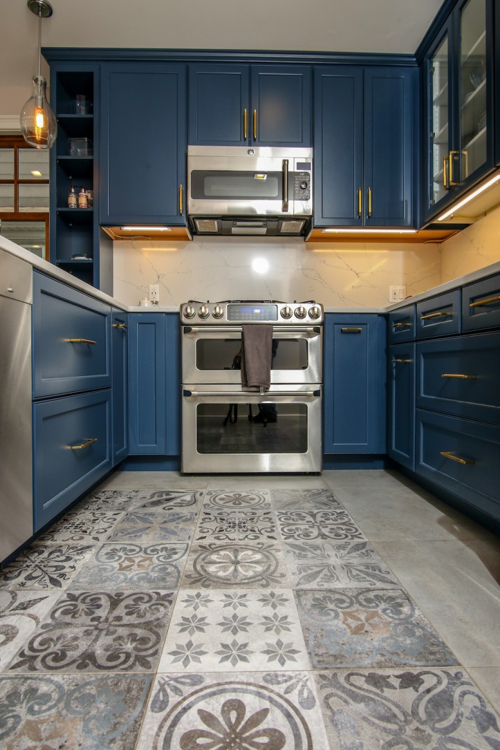 gray patterned floor tiles in a kitchen with blue kitchen cabinets and silver appliances after renovation 