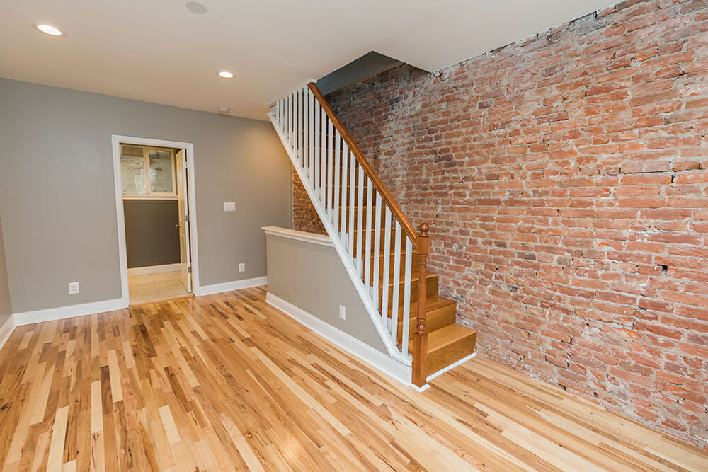 brown vinyl flooring and brick wall with brown staircase with white railing