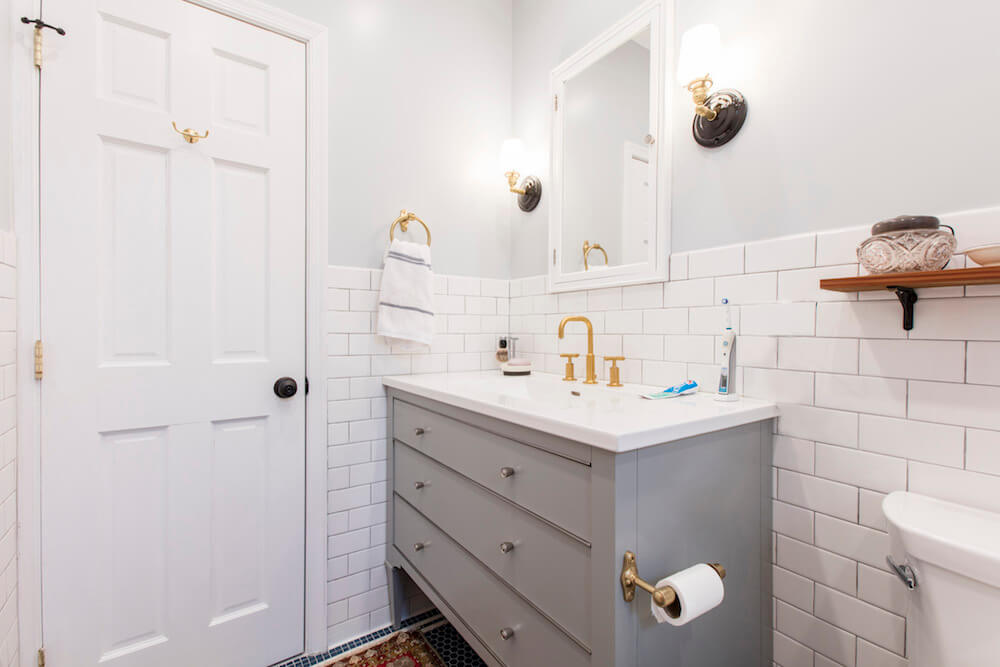 Half tiled white subway tiles in gray and white bathroom with gray floating vanity after renovation