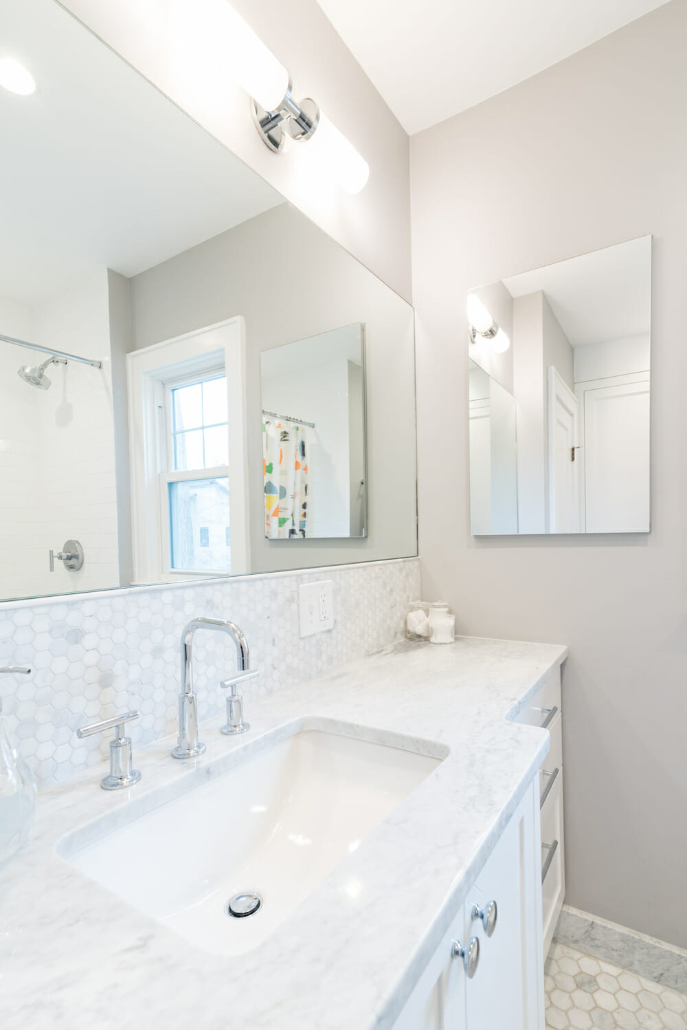 long bathroom mirror on a gray wall in a bathroom with white counter and sink after renovation  