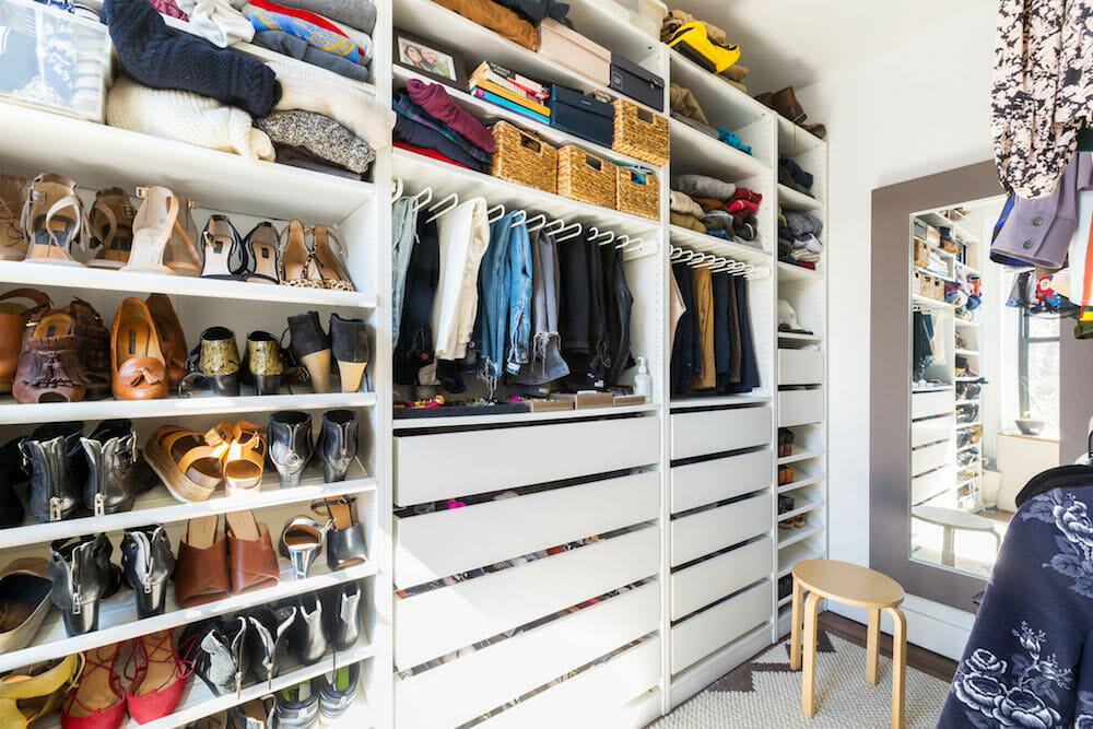 white walk in wardrobe with closed drawers and open shelves with clothes and shoes after renovation