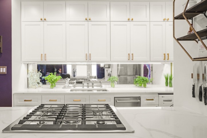 white kitchen cabinets in a white and purple kitchen with marble countertop and hob