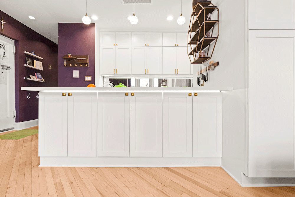 white kitchen peninsula with cabinets in an open kitchen and white and purple wall after renovation 