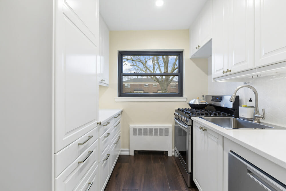 white kitchen cabinets and drawers with brushed steel faucet and sink near window after renovation 