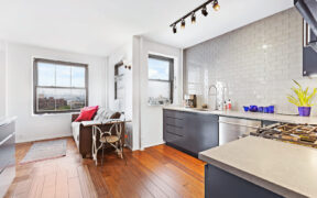 brown hardwood floor for open kitchen with blue kitchen cabinets and large window to living room after renovation