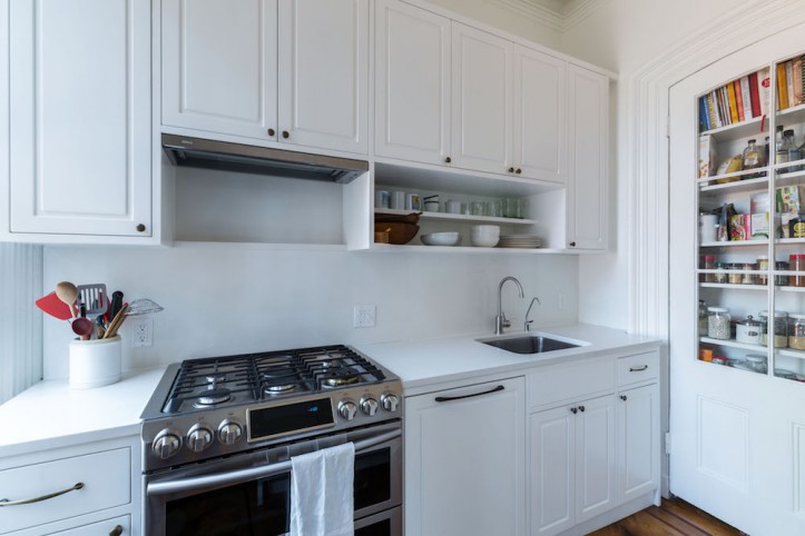 white overhead kitchen cabinets over white quartz counter and open shelves after renovation 