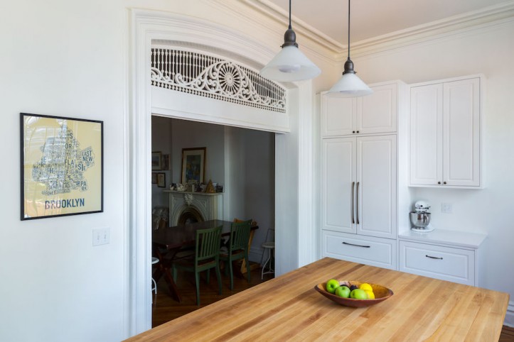 wide doorway to a white kitchen space with white cabinets and pendant lights after renovation