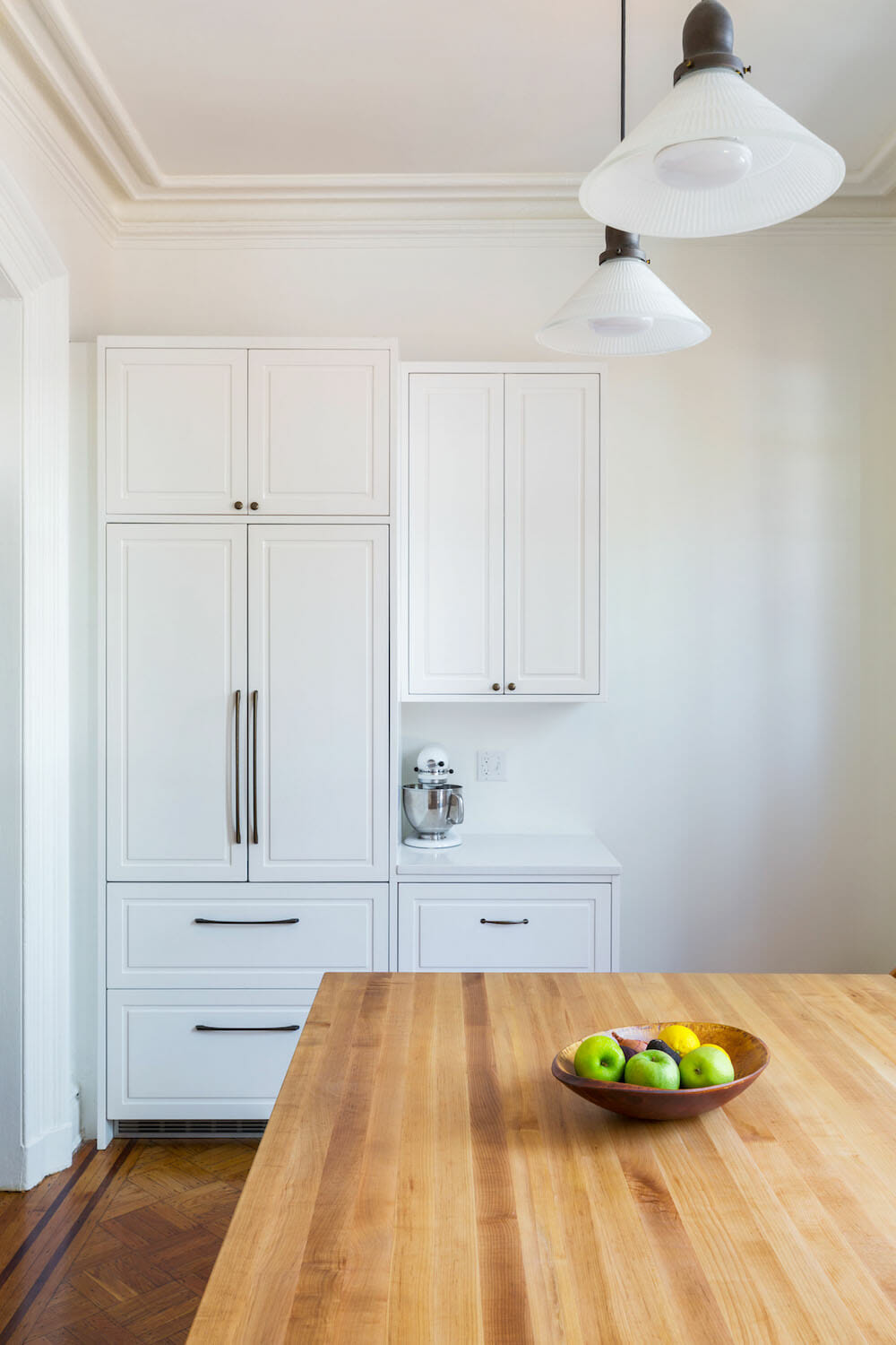 white cabinets and a small white counter along with brown dining table after renovation