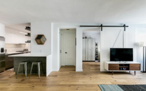 white living room with view of kitchen on light brown floor after renovation