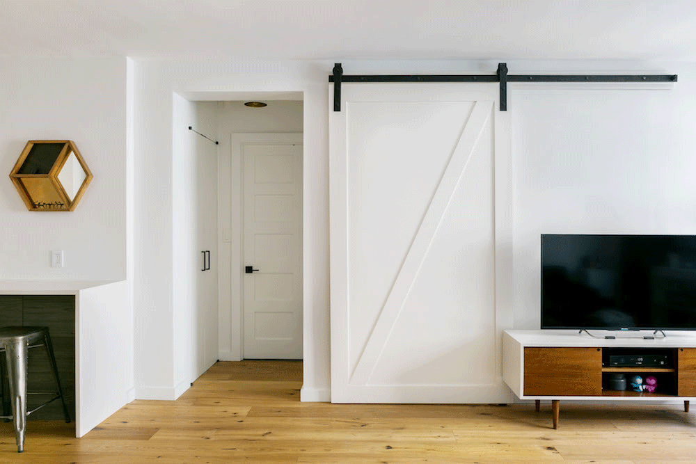 white barn door in a white living room with wooden floor after renovation