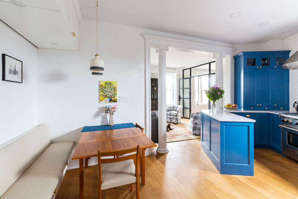 breakfast nook with built in bench in a white and blue open kitchen with kitchen peninsula after renovation