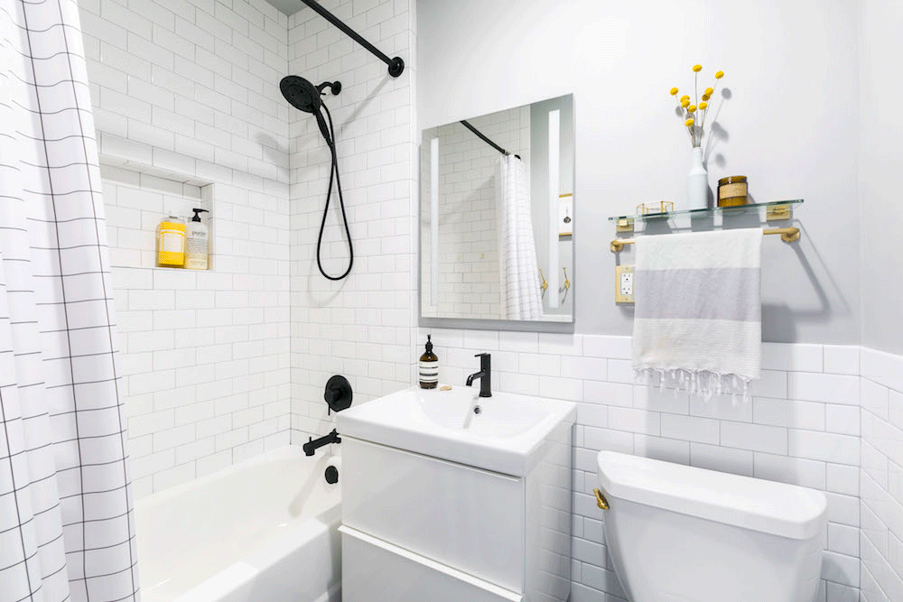 white and gray bathroom with white subway tiles and white floating vanity after renovation