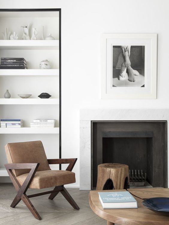 black fireplace in a white room with white open shelves and brown flooring after renovation