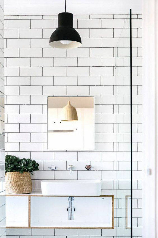 white subway tiled wall with black hanging pendant light  and white basin sink and floating vanity 