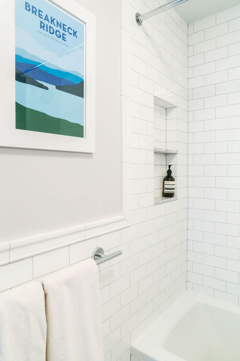 White and gray bathroom with white subway tiles and recessed shower shelf after renovation