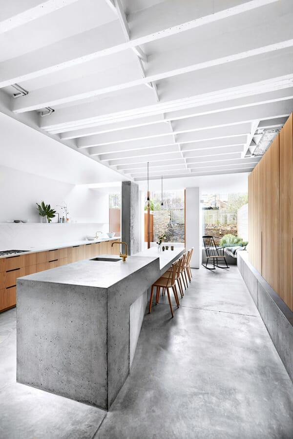 gray kitchen island in a concrete flooring and brown kitchen cabinets after renovation