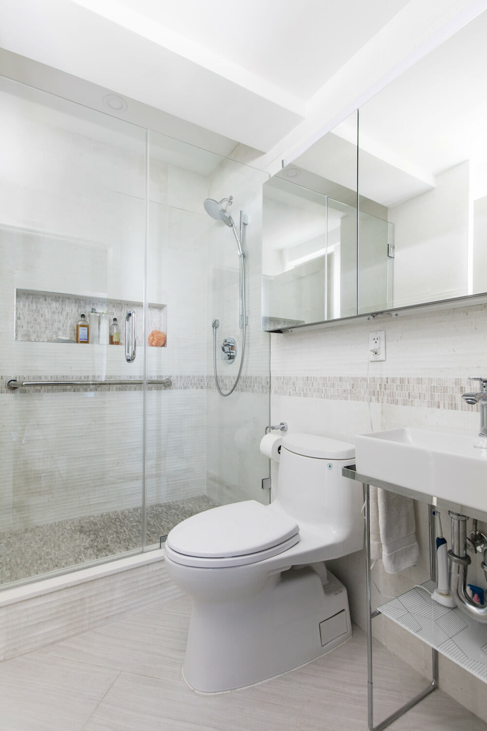 A remodeled bathroom with step-in shower, glass door and shower niche storage