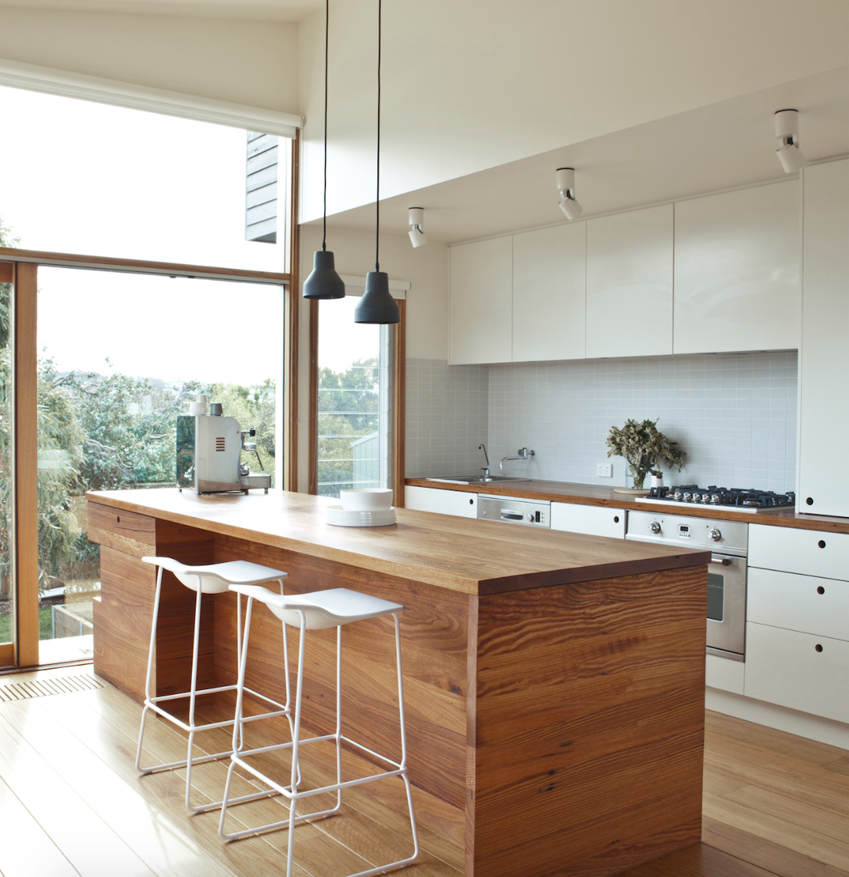 kitchen, waterfall island, warm wood, hardwood floors, pendant lighting, tile backsplash, white cabinets, bar seating