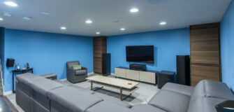 Seating area with plush gray seater and home theater with carpeting and blue walls after renovation