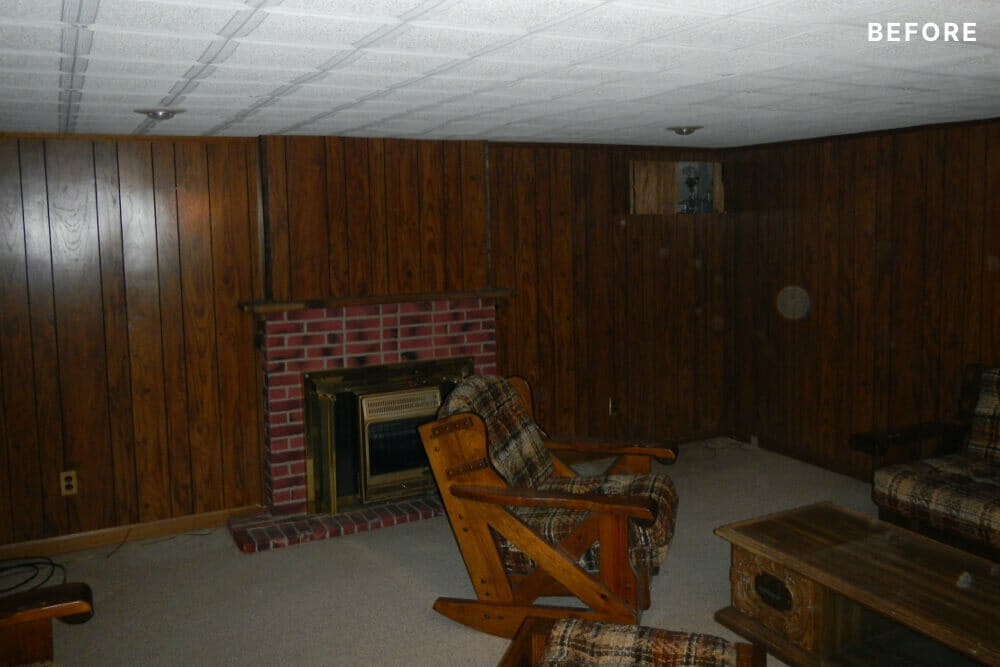 Brown shiplap walls and white low roof with brick fireplace before renovation