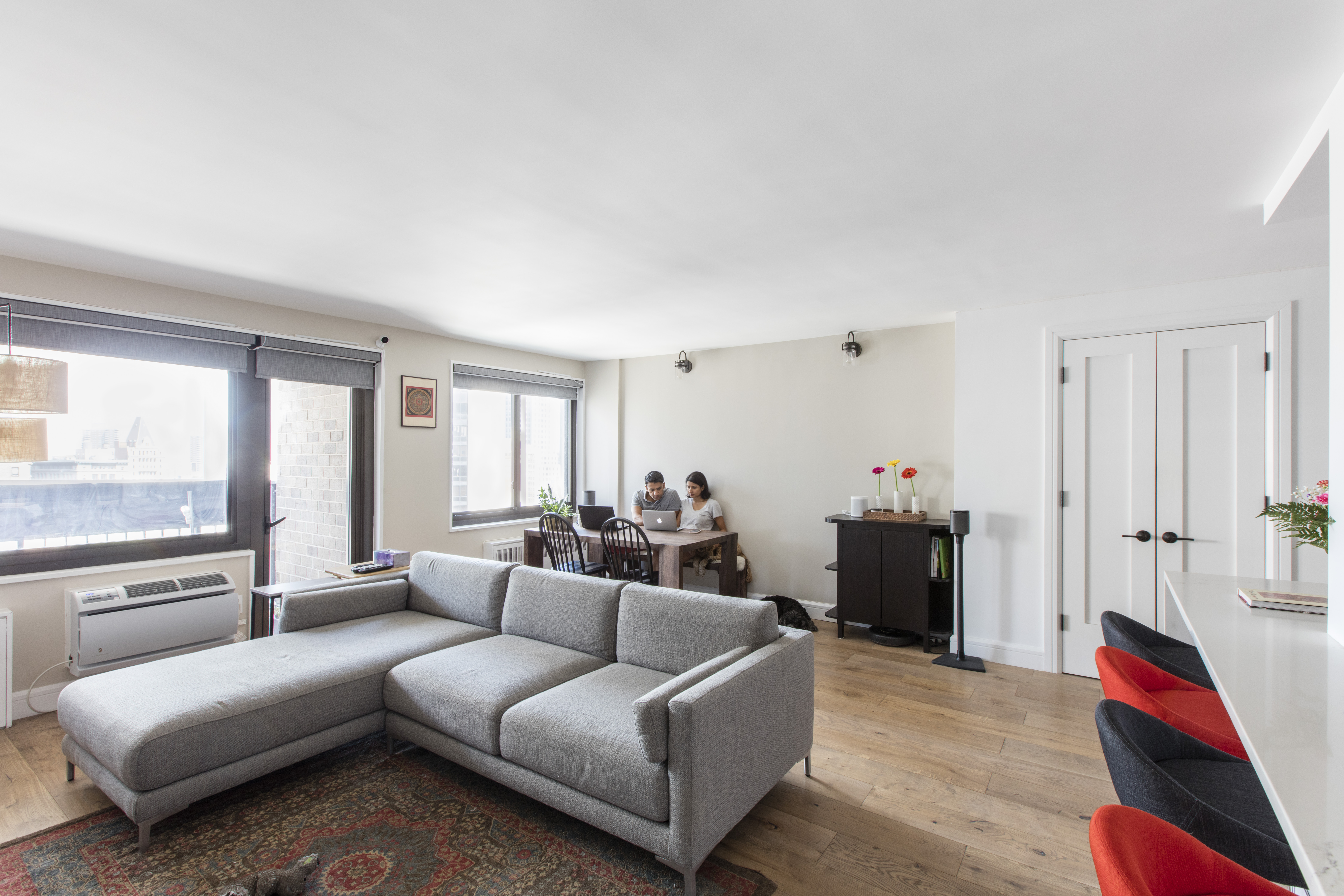 Wide oak flooring spans the living and dining area beside the open kitchen, bringing the Financial District apartment's shared spaces together.