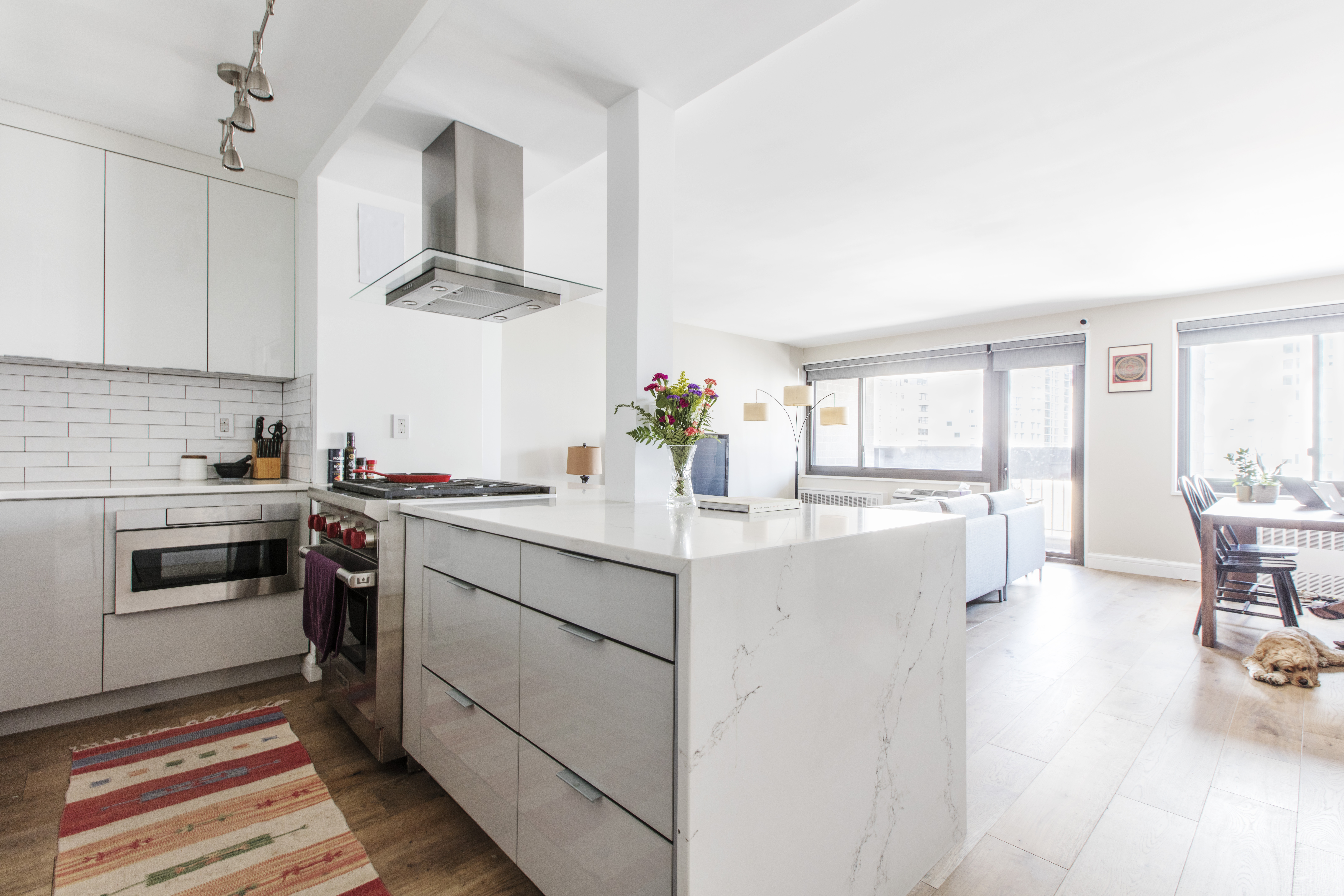 Wide oak flooring continues from the open kitchen into the living and dining areas, paired with white finishes in this Financial District home.