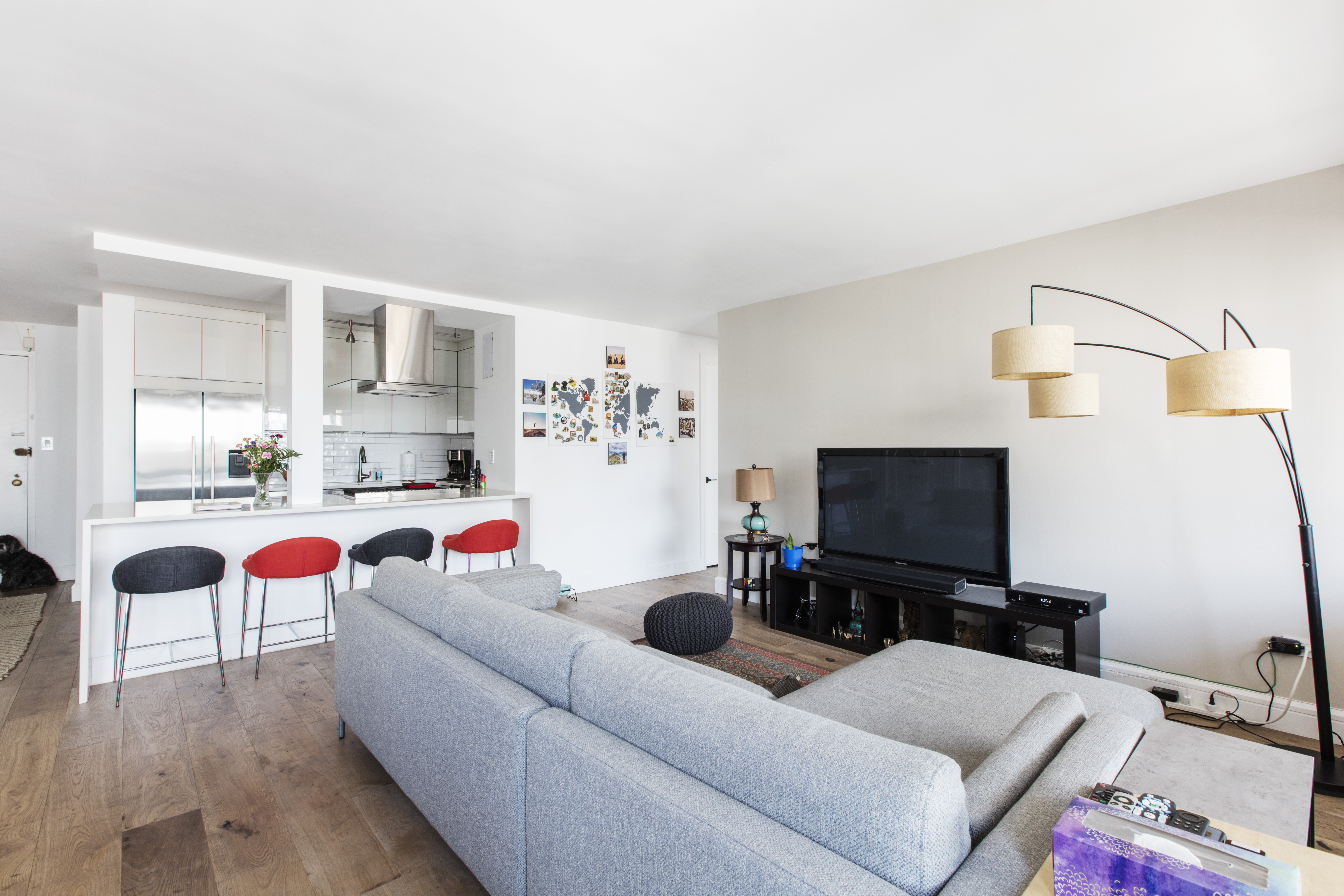 Wide plank oak flooring runs across a New York City living room and into the open kitchen, creating continuity between the renovated spaces.