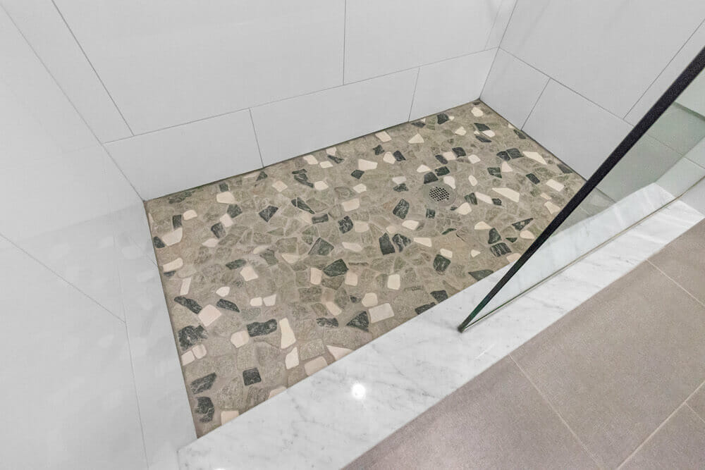 White walk in shower area with stone effect flooring after renovation