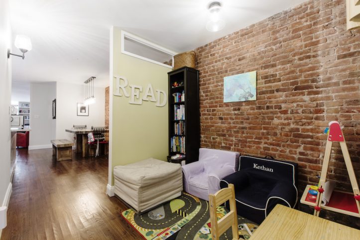 play or game room with hardwood floors and exposed brick wall and half partition wall to dining room after renovation
