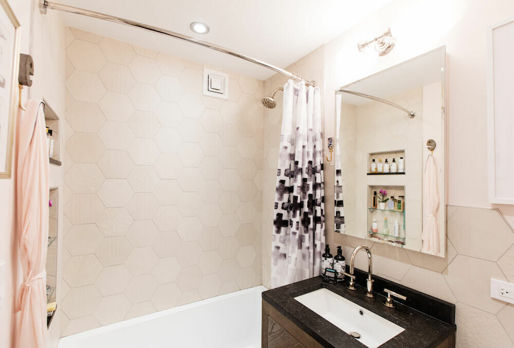 Hexagon tiled shower wall with large vanity mirror over sink and backsplash after renovation