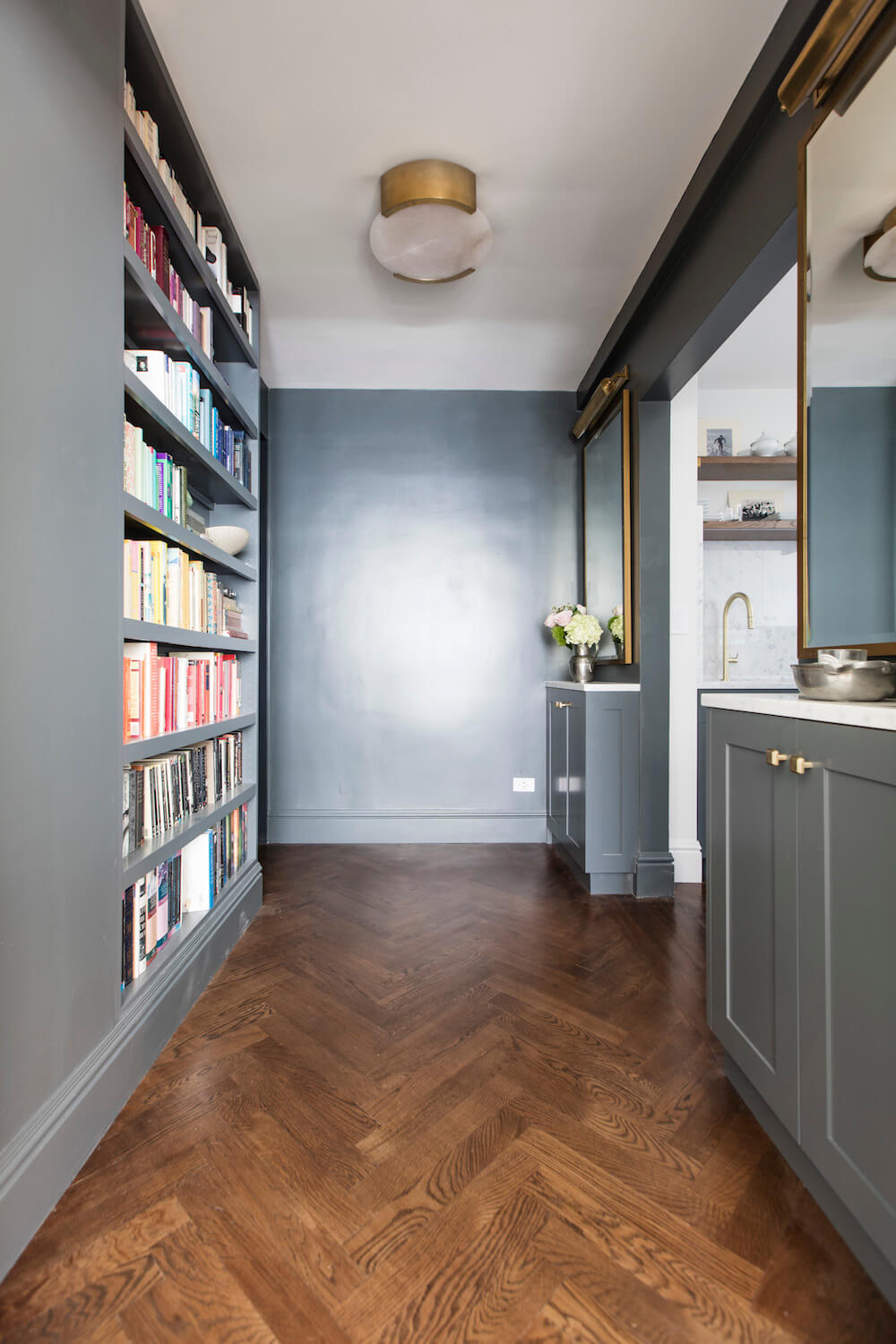 Gray foyer with full length bookcase and brown wood floor after renovation