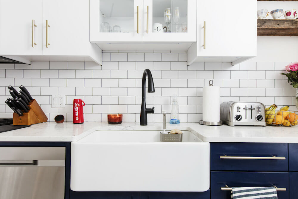 kitchen with white overhead cabinets and white countertop with farmhouse sink and backsplash with white subway tiles after renovation