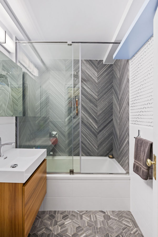 chevron tile in shower with tub and wallpaper
