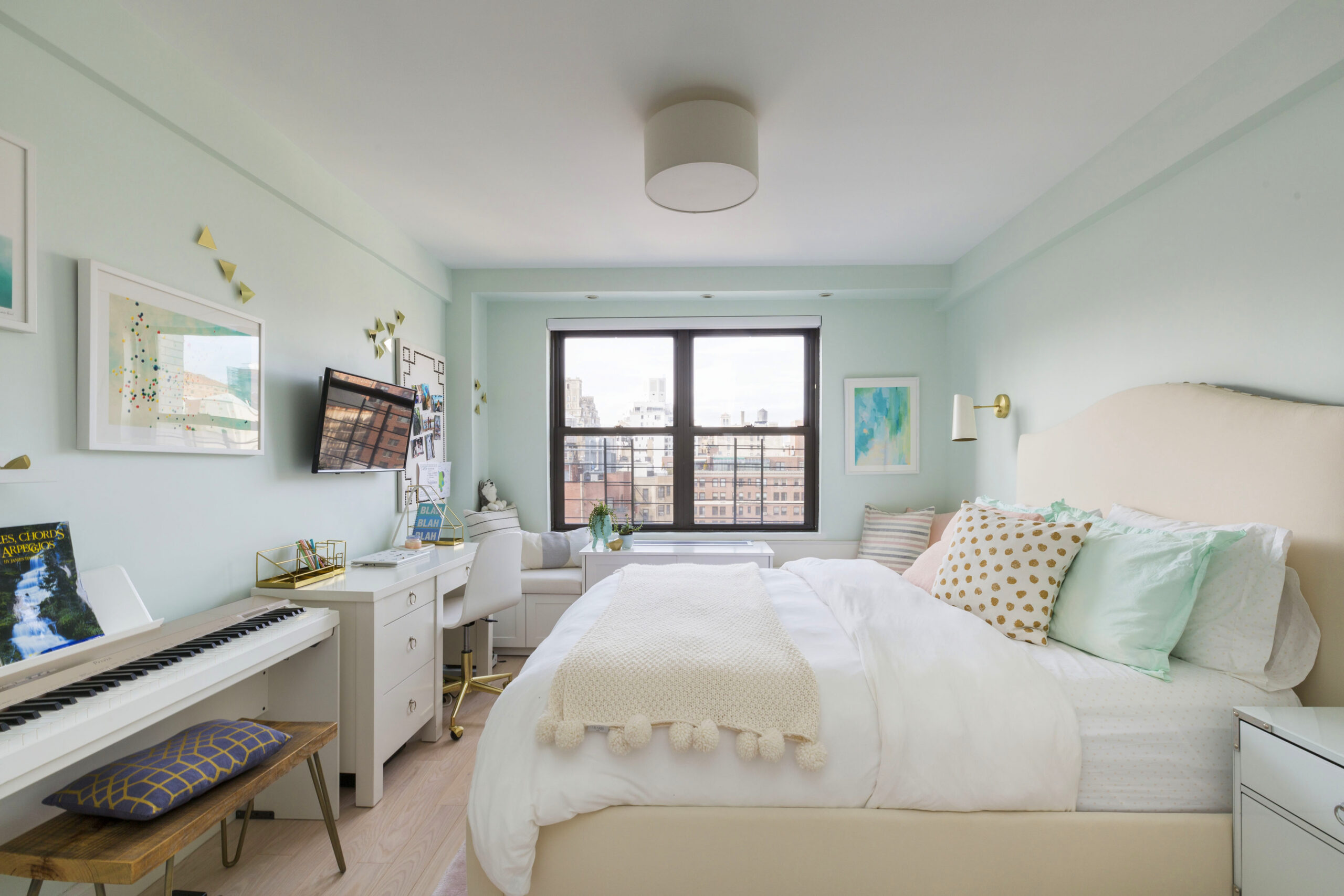 Upper East Side daughter’s bedroom with mint walls, desk area, window bench storage, piano, wall art, and soft bedding after the co-op renovation.